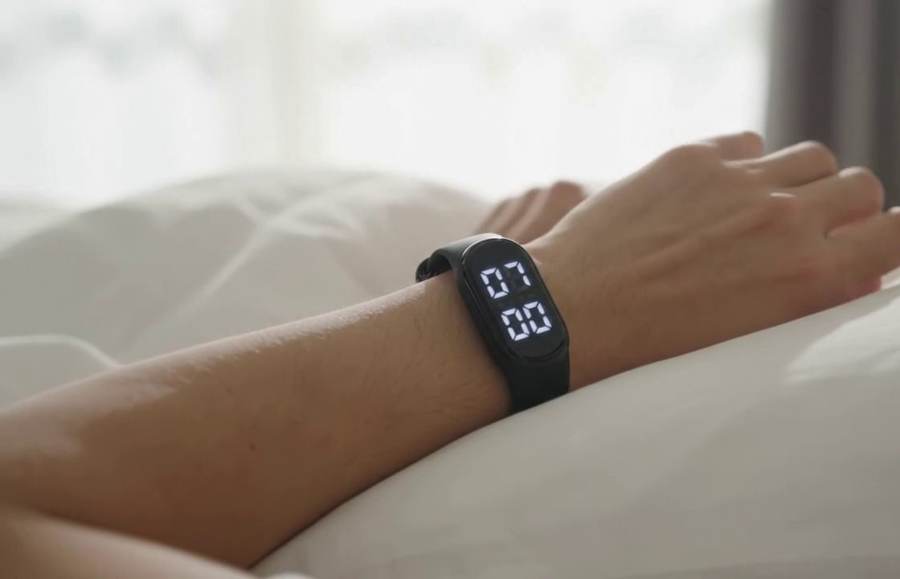 Band worn on the wrist of a sleeping person, display reading 07:00